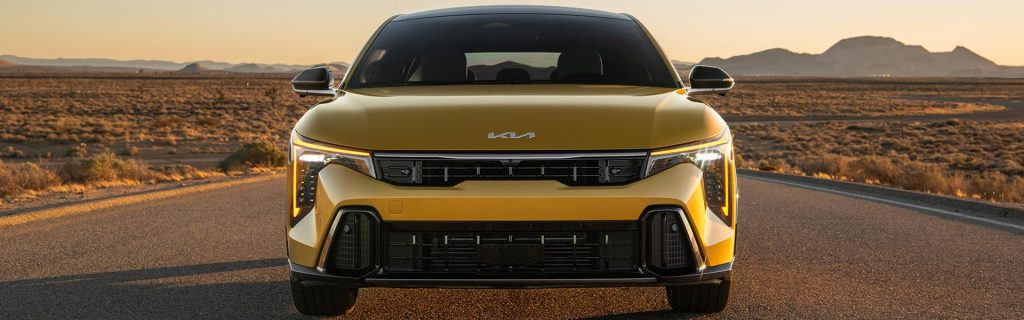 Kia K4 Hatchback driving on an open road at sunset, showcasing bold design, fuel efficiency, advanced safety technology, and modern performance.