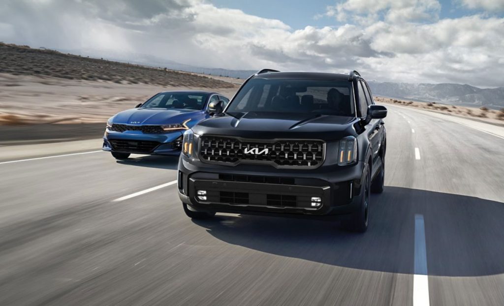 Kia models running in the road surrounded by desert.